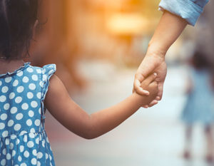 A child and an adult holding hands from behind